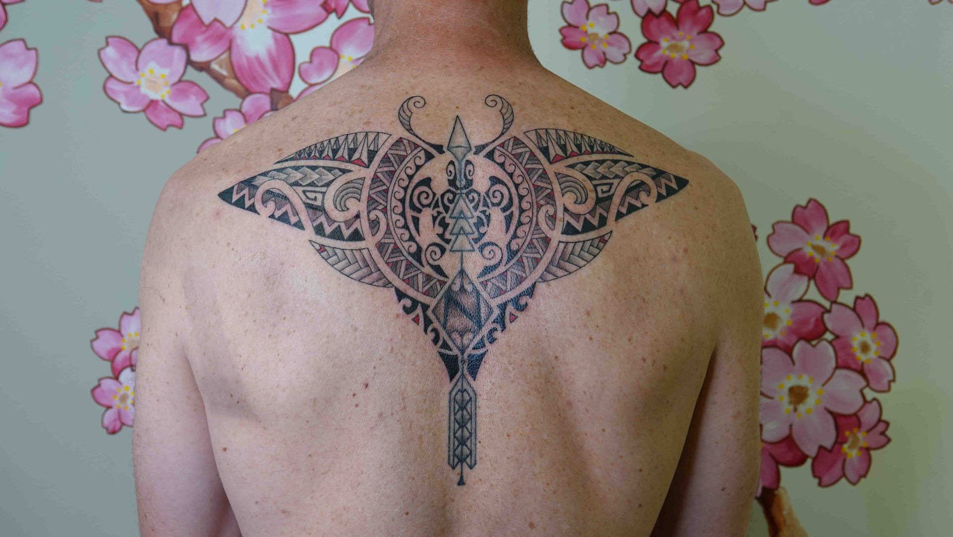 Groot symmetrisch ornament over de schouderbladen