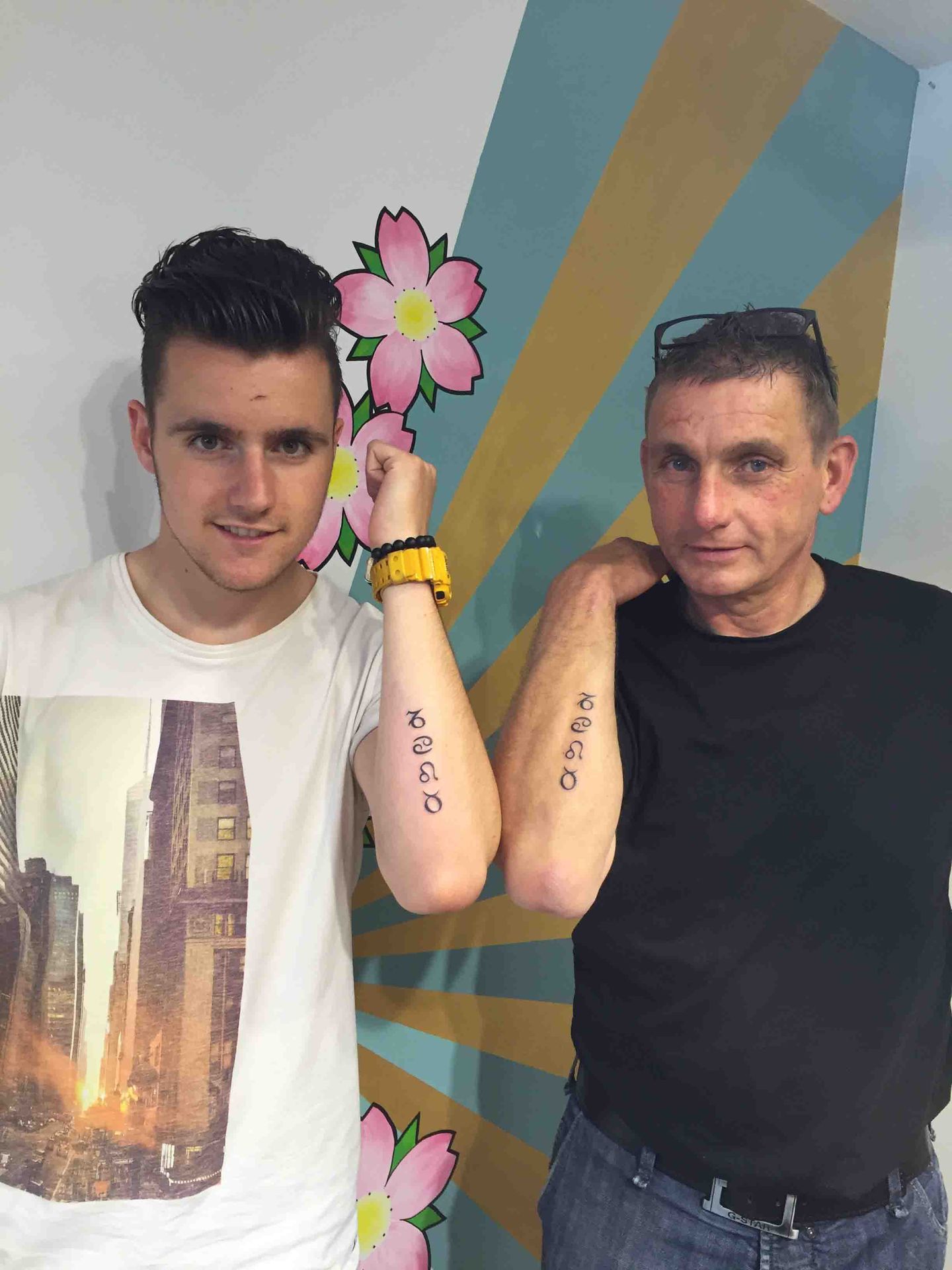 Vader en zoon laten hun gelijke tatoeage op de onderarm zien