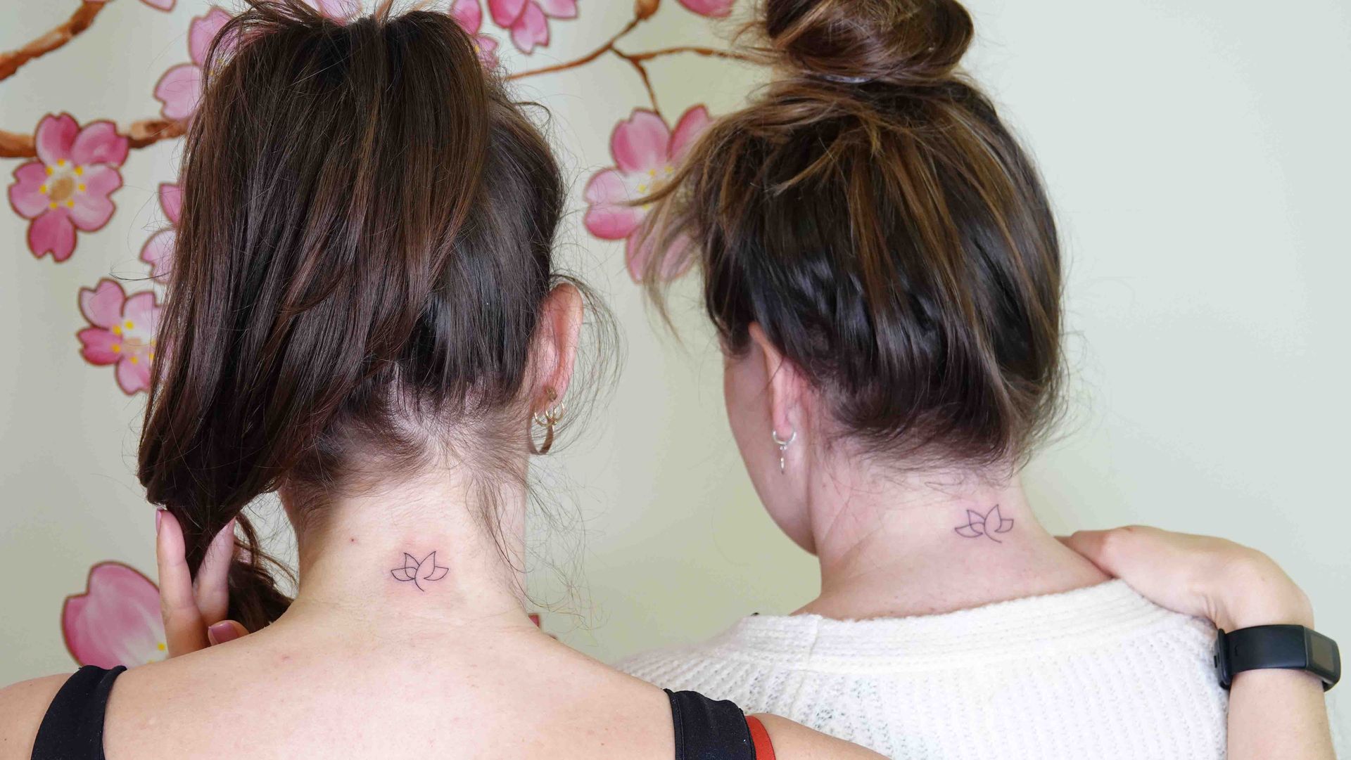 Twee nekken naast elkaar, allebei met dezelfde kleine tatoeage