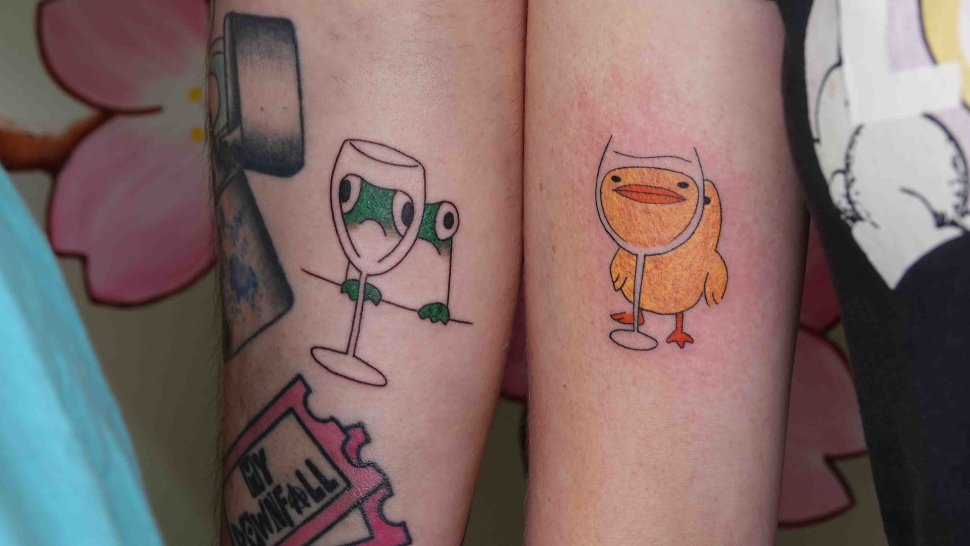 Twee kuiten naast elkaar met vrolijke tekenfilmtatoeages van drankjes