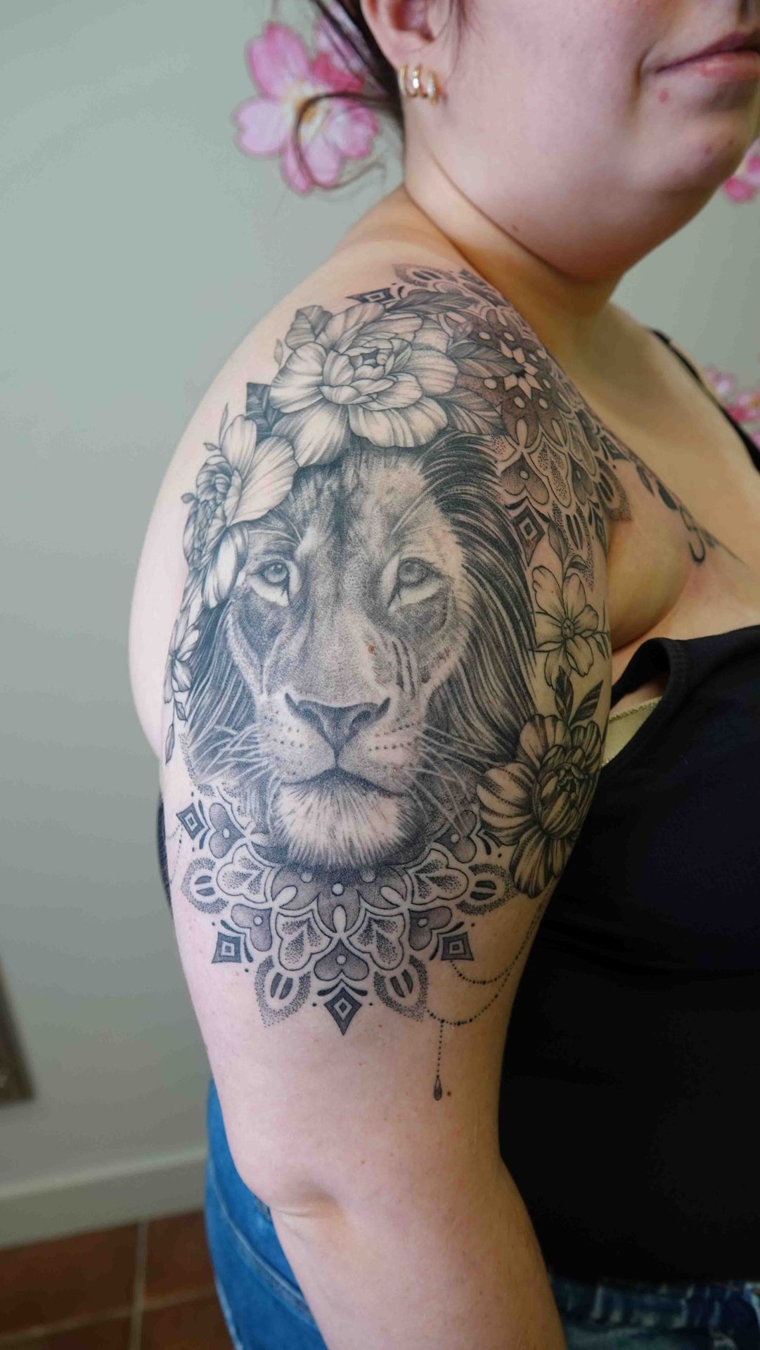 Leeuwenkop met een bloemenkrans en een mandala, op een bovenarm
