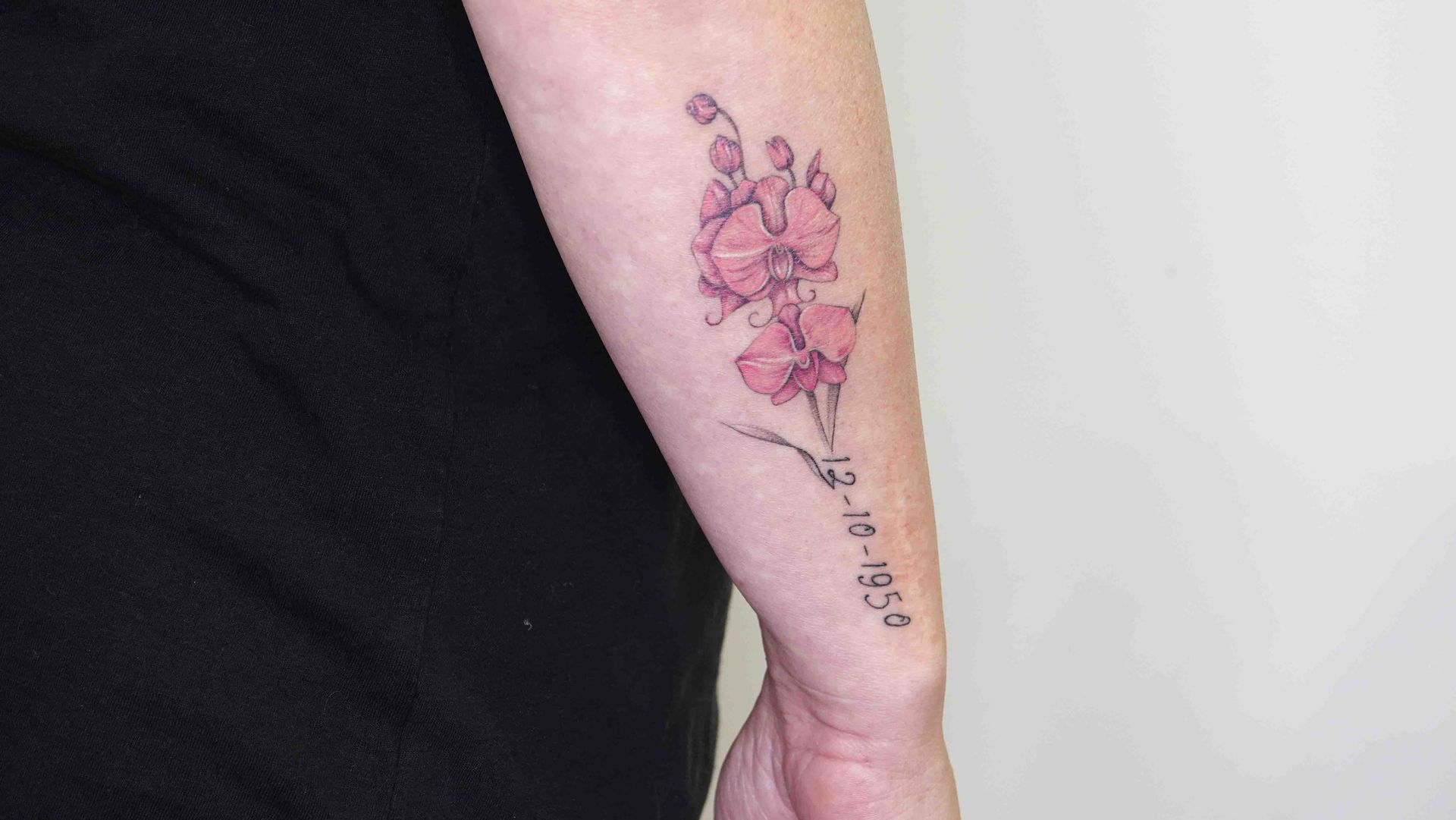 Roze bloesem met een dunne regel tekst op een onderarm