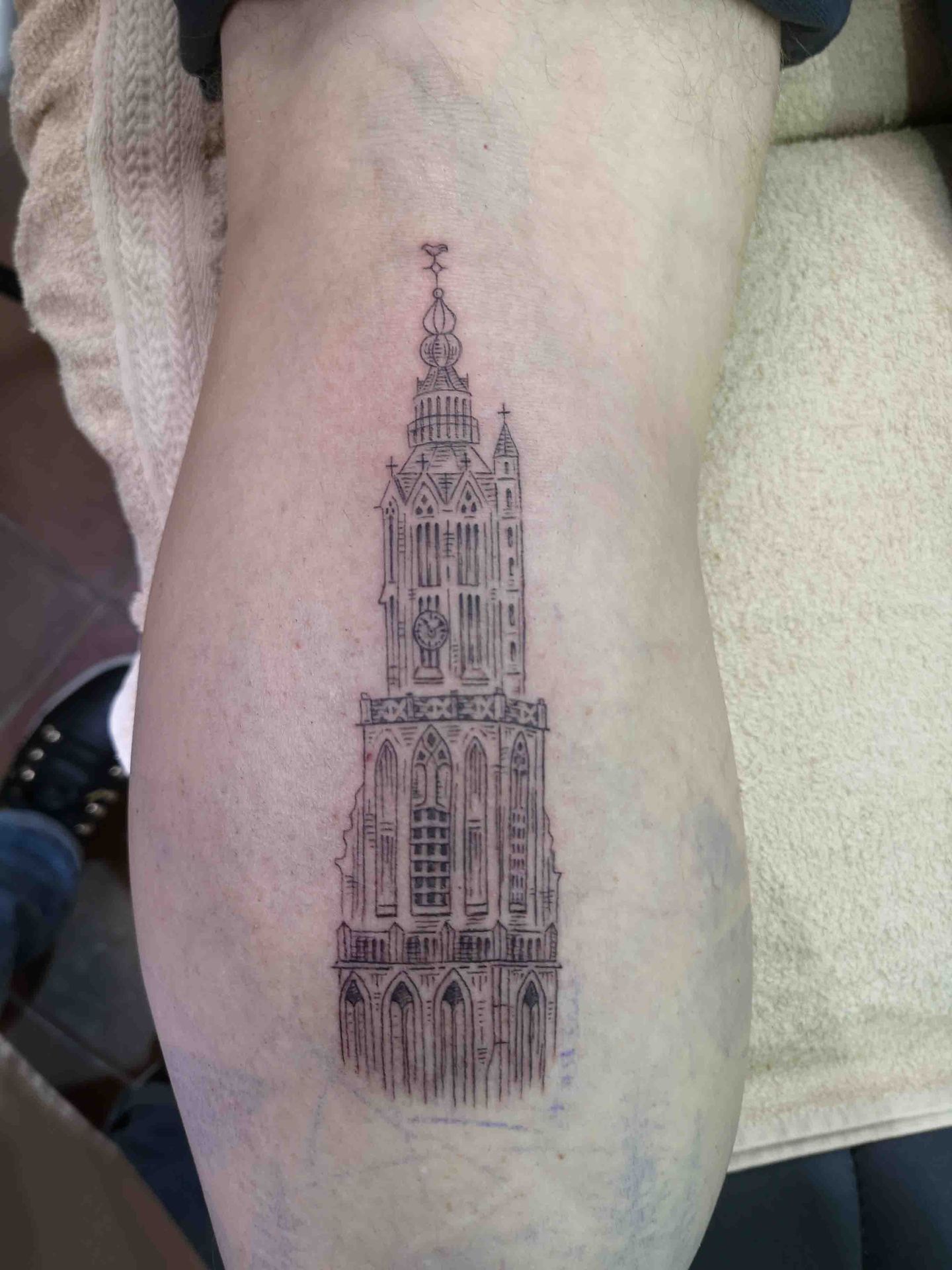 Gedetailleerde gotische kerktoren in fijne lijnen op een bovenbeen