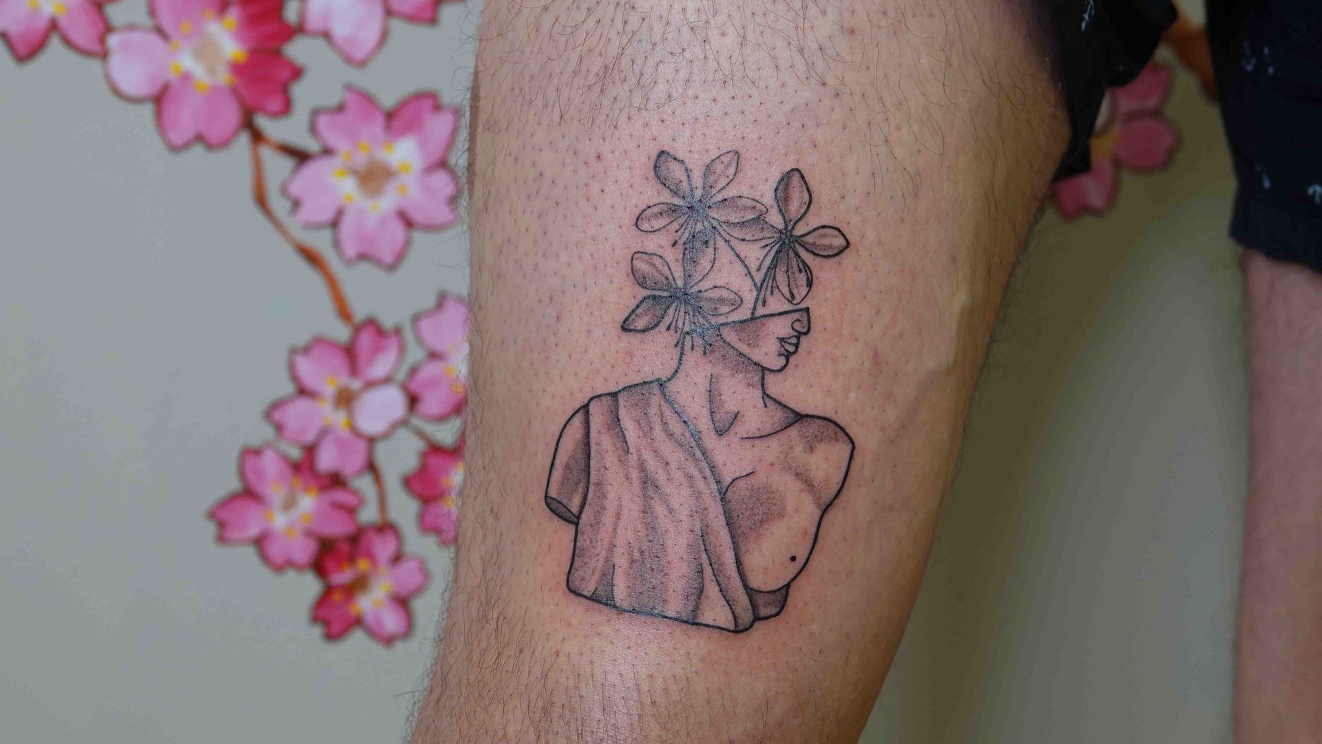 Vrouwenbuste met bloemen in het haar, in fijne lijnen op een bovenarm