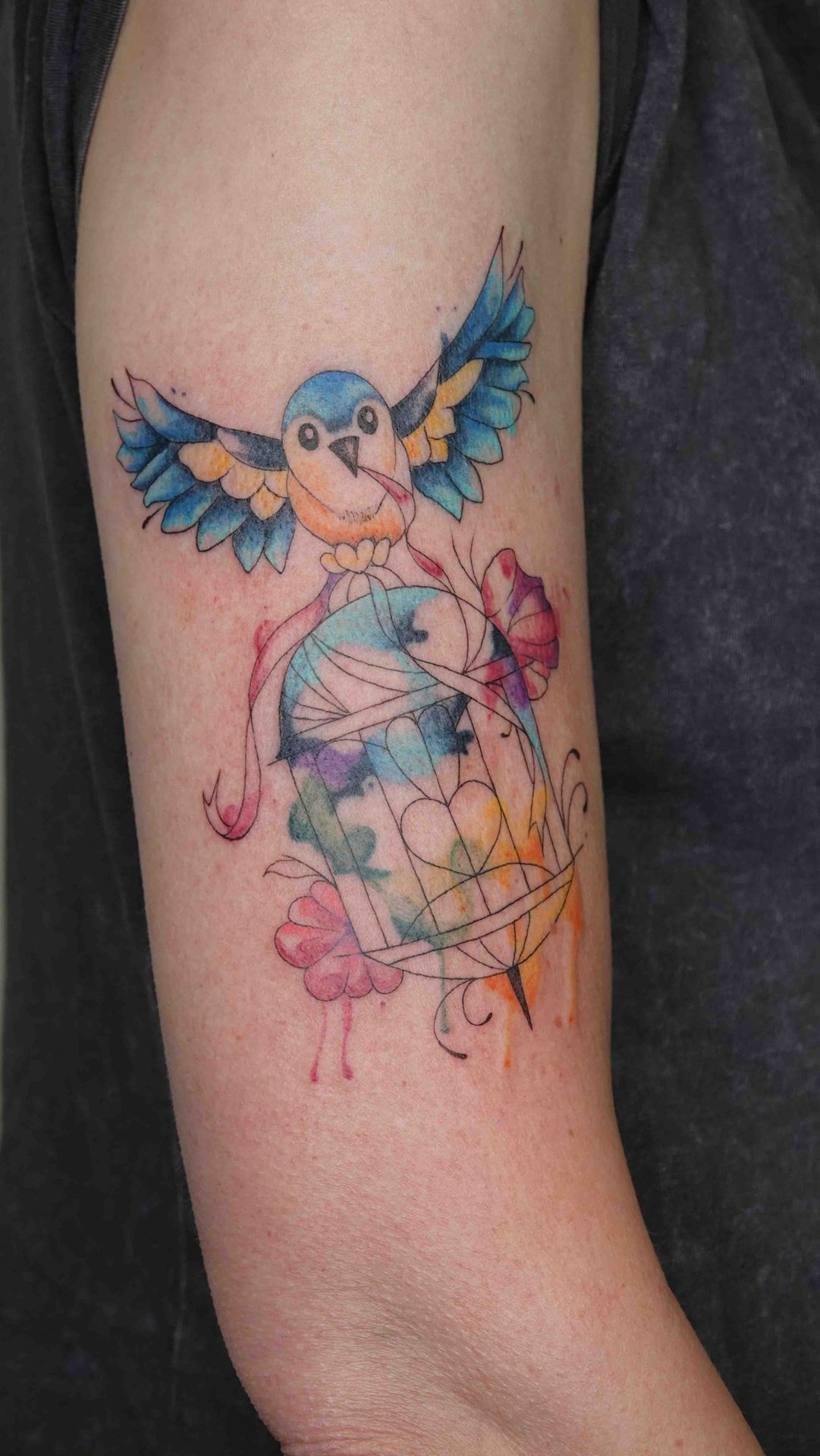 Blauwe vogel bij een vogelkooi in waterverfstijl op een bovenarm