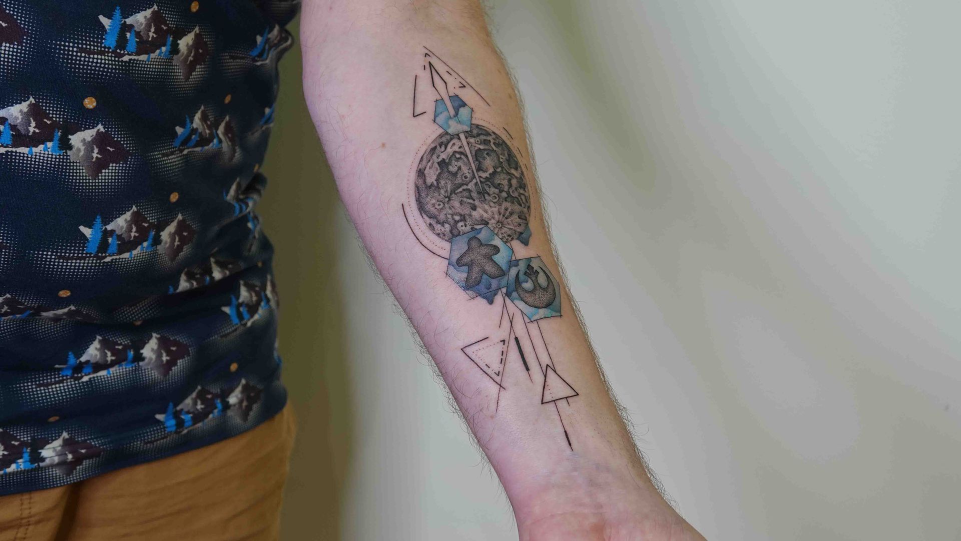 Geometrische tatoeage op een onderarm met een rond ornament, driehoeken en losse lijnen