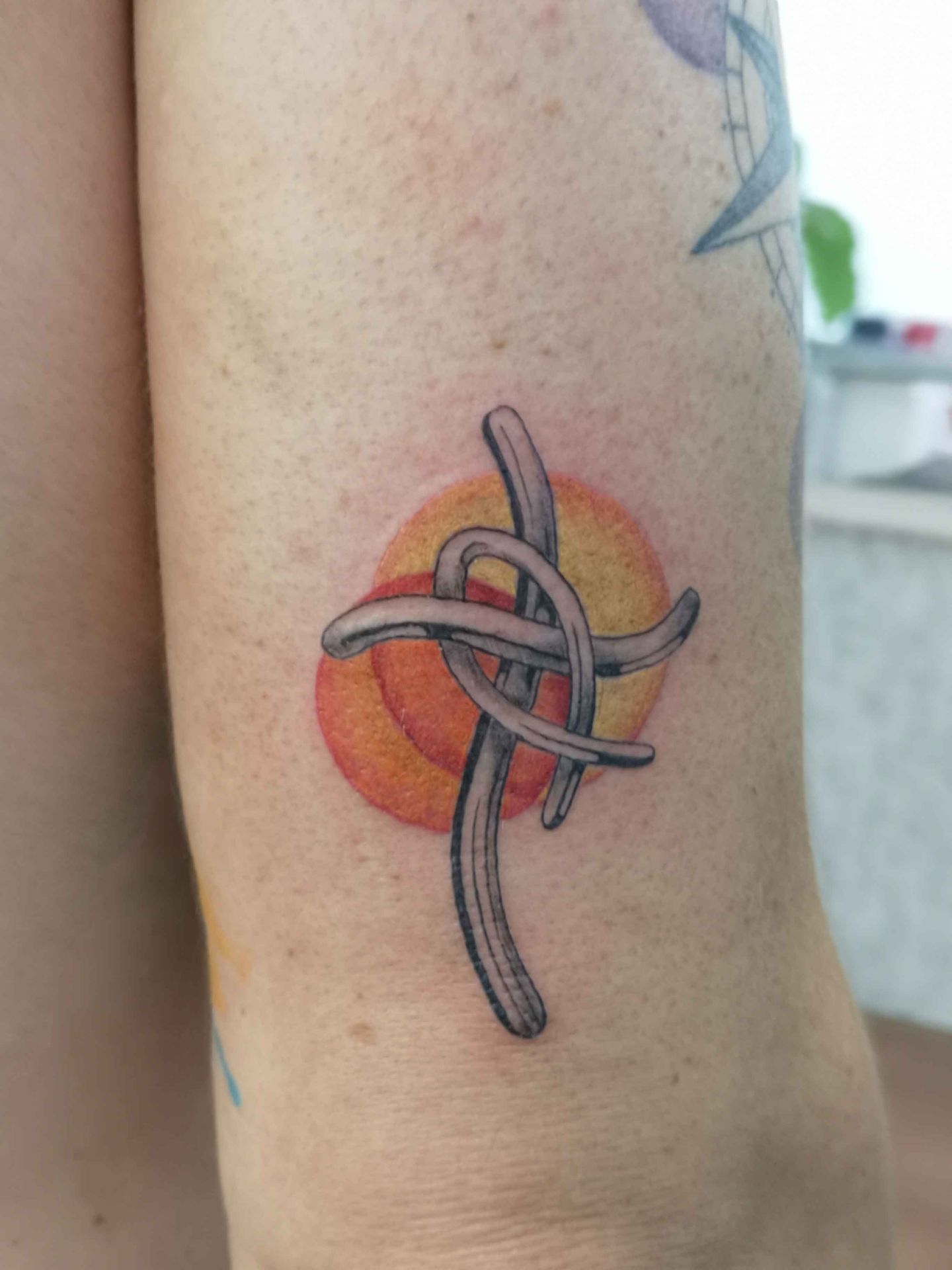 Grijze geknoopte lintvorm voor een oranje zon, op een bovenarm