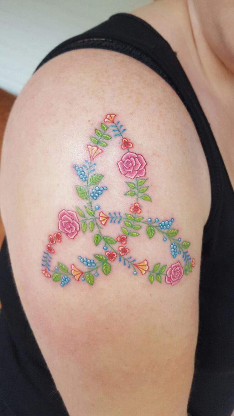 Driehoekig bloemornament in roze, blauw en groen op een schouder