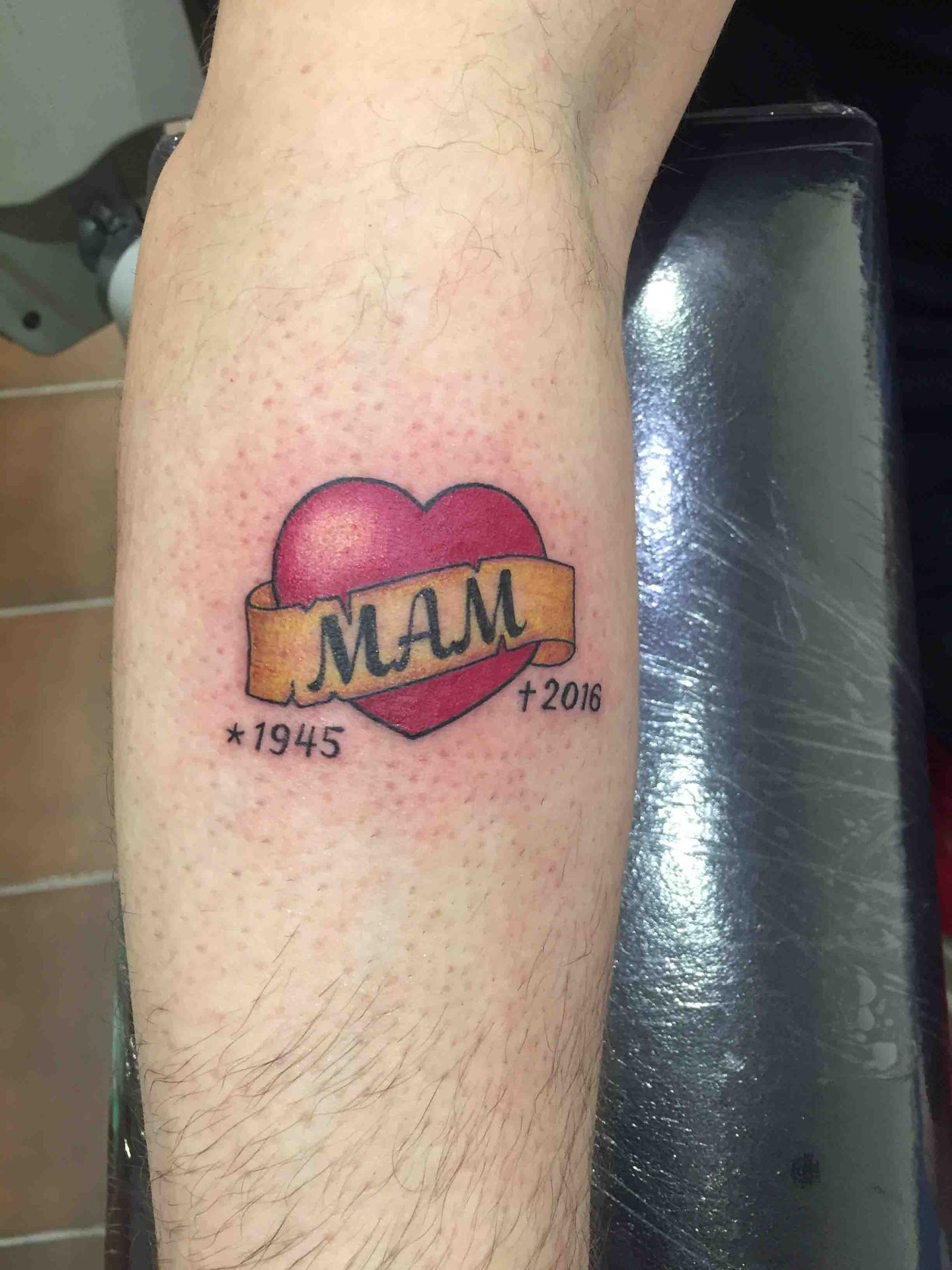 Rood hart met een banderol waarop MAM staat, met twee jaartallen eronder