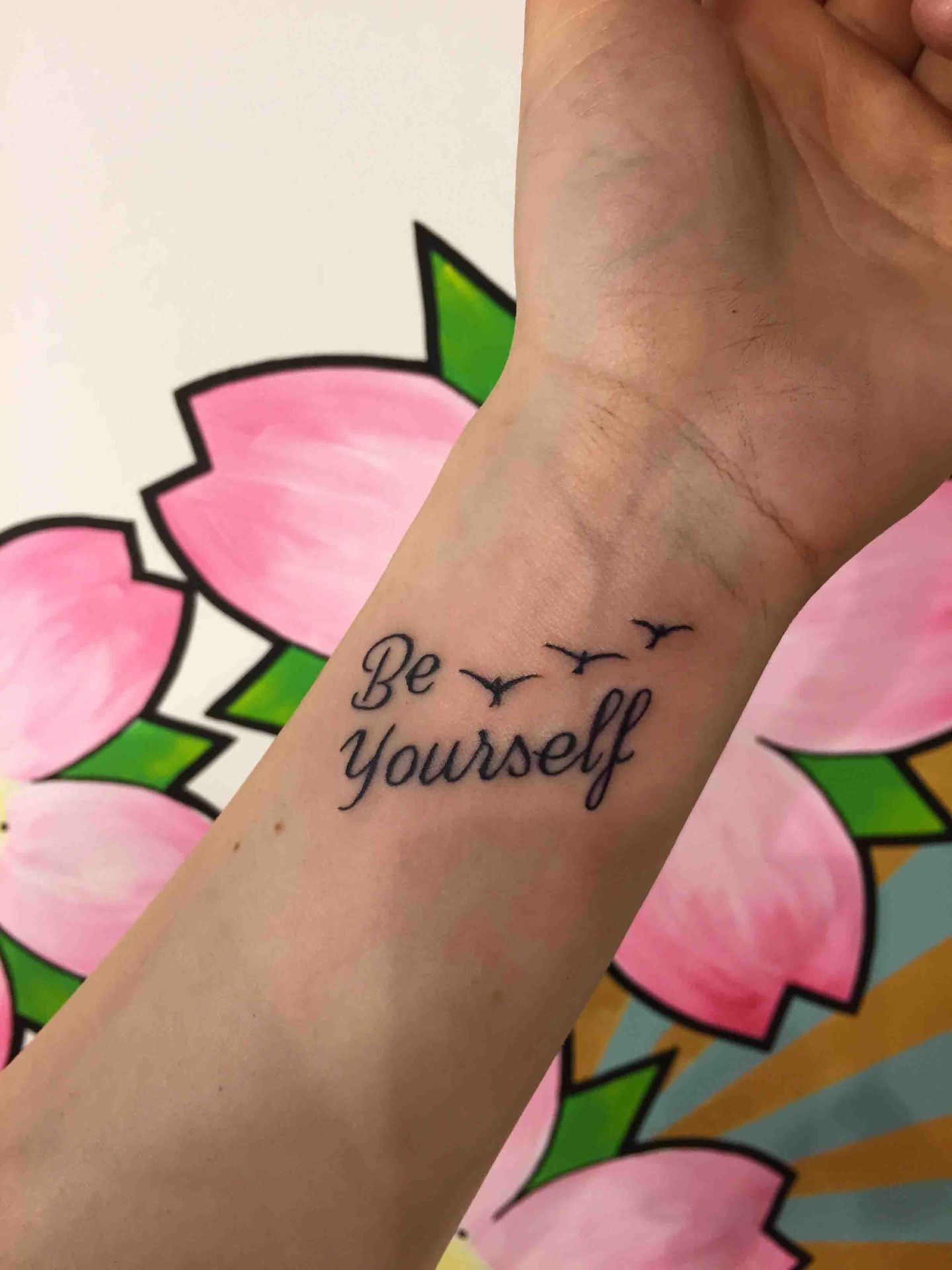 De woorden Be yourself met kleine vogeltjes op een pols