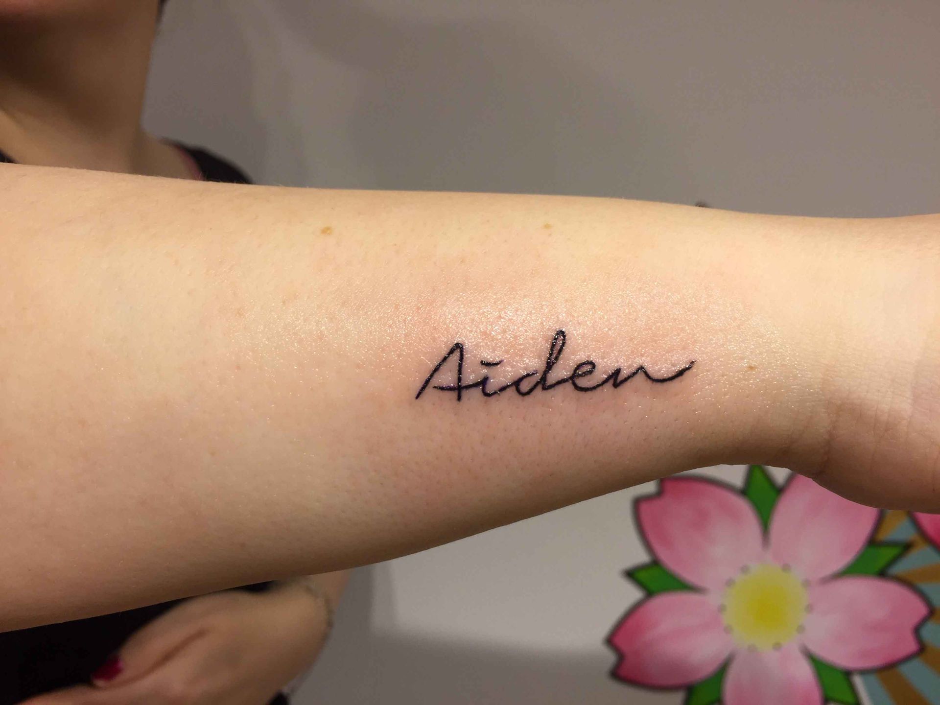De naam Aiden in handschrift op een onderarm