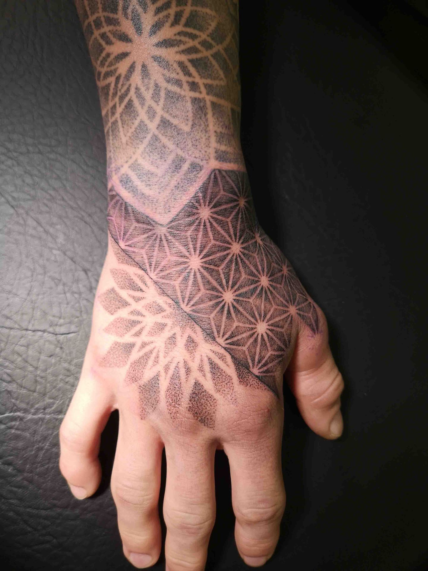 Geometrisch stippelwerk over de rug van een hand, met een mandala en een ruitpatroon