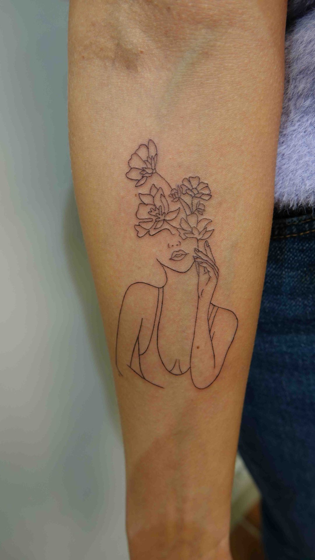 Vlinder tussen bloemen in fijne lijnen op een arm